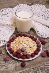 oatmeal with cherries and a glass of milk with a crocheted doily on a wooden table