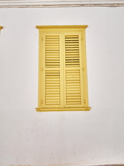 yellow window shutters on pale white wall