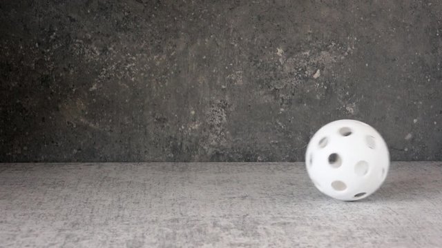 White floorball rolling and bouncing in slow motion