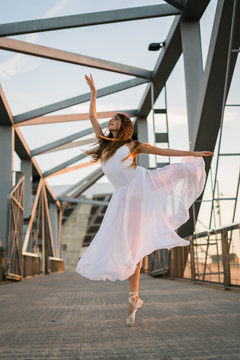 Young ballerina performing under modern construction