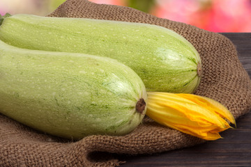 two courgettes with a flower on sackcloth wooden background