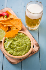 Nachos, guacamole and beer on blue wooden table

