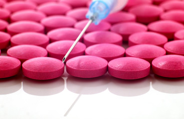 a lot of red pills and a syringe, macro, shallow depth of field, focus on needle tip