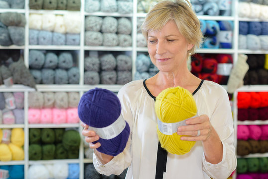 Lady in shop choosing between two balls of wall