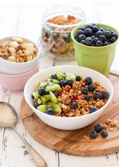 Healthy breakfast; Homemade granola with kiwi, blueberries and nuts in white bowl