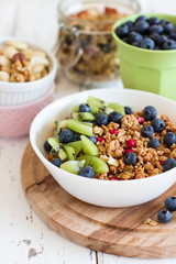 Healthy breakfast; Homemade granola with kiwi, blueberries and nuts in white bowl; Close up
