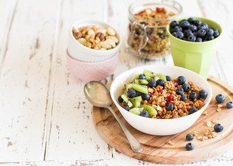 Healthy breakfast; Homemade granola with kiwi, blueberries and nuts in white bowl