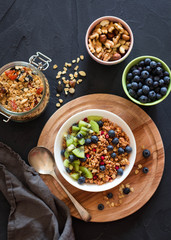 Healthy breakfast; Homemade granola with kiwi, blueberries and nuts in white bowl; Overhead shot