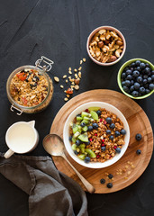 Healthy breakfast; Homemade granola with kiwi, blueberries and nuts in white bowl; Overhead shot