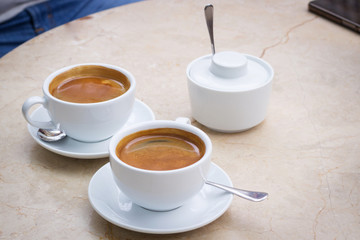 White cups of coffee and sugar bowl on marble table