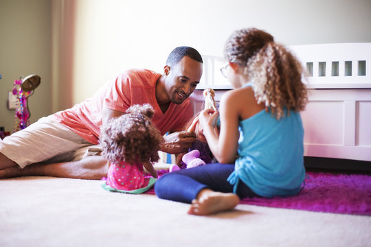 Father And Daughter Playing Together With Dolls At Home