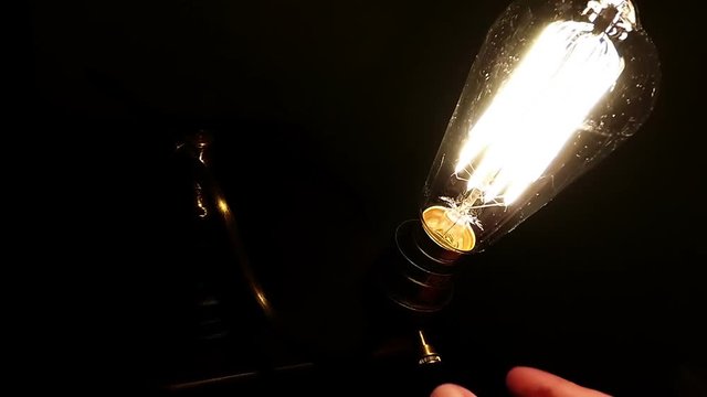 A vintage bulb turns on and off in old light lamp plus flickering.