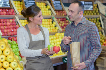Man buying apples in greengrocers