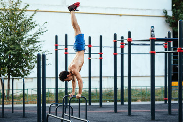 Muscular man at crossfit ground doing push ups as part of training. Sport concept