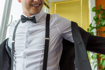 Groom wearing suspenders suiting up.