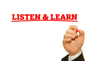 Businessman hand writing LISTEN AND LEARN message on a transparent wipe board.