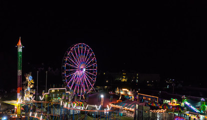 view of the county fair at night with colorful lit rides
