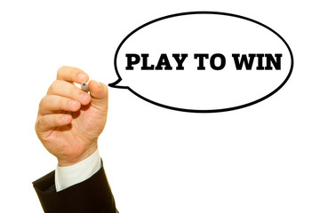Businessman hand writing PLAY TO WIN message on a transparent wipe board.