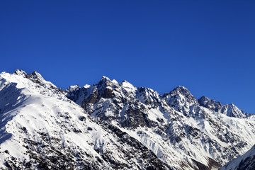 Fototapeta na wymiar Snowy rocks and blue clear sky at cold sun day