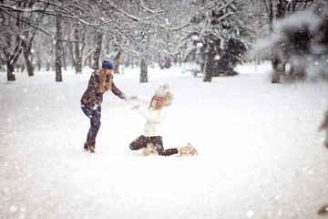 Fototapeta na wymiar Two girls friends or sisters playing snowballs in the snow in the winter in a warm winter clothes