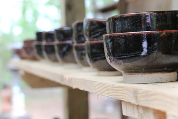 brown clay bowls on a plain wooden shelf 