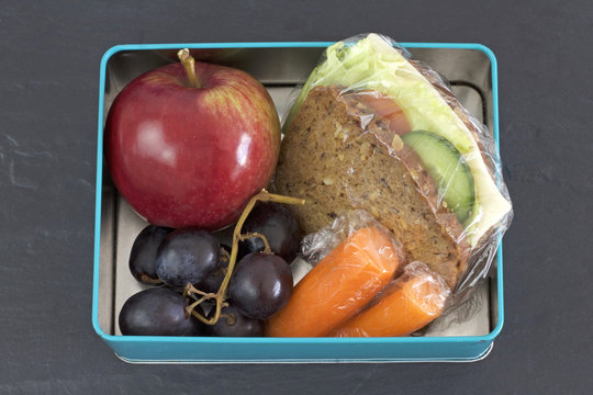 Healthy lunch box, cheese sandwich, apple, carrots, and grapes . Topview image