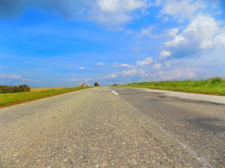 Asphalt road between fields during sunny day
