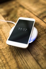White smartphone charging on a charging pad. © Daniel Jędzura