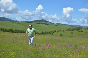 Fototapeta na wymiar Man is running in a meadow on Zlatibor Mountain surrounded by wildflowers in springtime