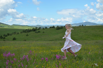 Woman in a dress with floral pattern joyfully dancing in a meadow on Zlatibor Mountain