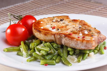 Two pieces of fried pork loin with vegetables on a white backgro