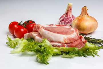 Two pieces of pork loin with salad and vegetables on white backg