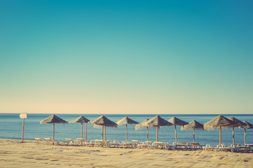 Beautiful view of beach with wicker umbrellas on the sunny blue sky outdoors background