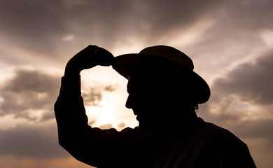 silhouette of a man with a hat on sunset background