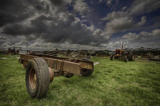
Old agricultural machinery in a field under a dynamic cloudy blue sky

