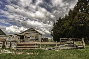 Fototapeta na wymiar Old dilapidated shearing shed against a dynamic cloudy blue sky background 