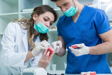 Dental prosthesis, dentures, prosthetics work. Prosthetics hands while working on the denture, false teeth, a study and a table with dental tools.
