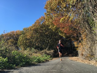 Man running on country road with autumn leaves