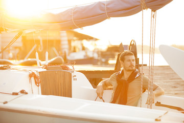 Handsome man on a sailing boat in sunset