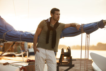 Handsome man on a sailing boat in sunset