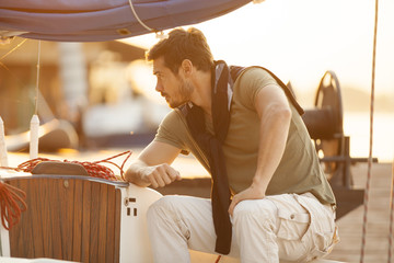 Handsome man on a sailing boat in sunset