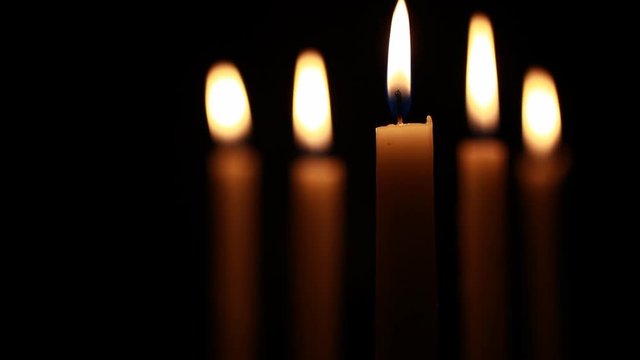 Five candles burning with selective focus on center candle.