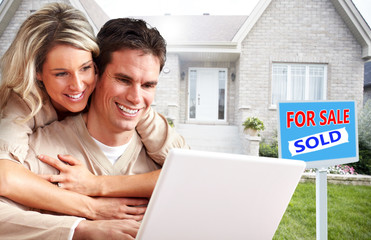 Couple with laptop near new house.