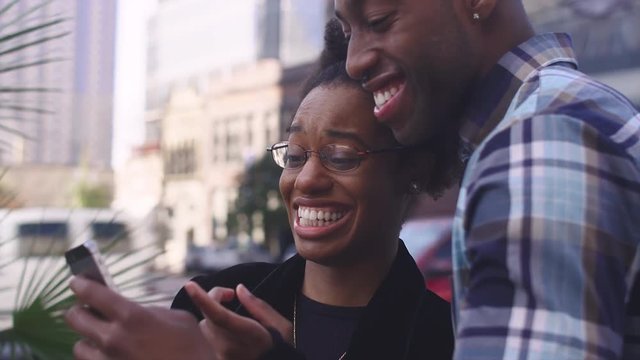 African American couple in a city taking pictures together with a cell phone, close up