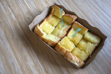 Toast with butter and condense milk in a paper plate on the wooden table (with copy space)