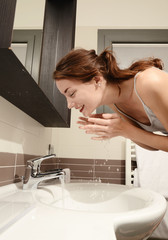 young  woman in bathroom wash  his face