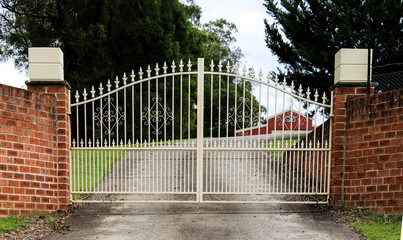Wrought iron metal driveway entrance gates in brick fence