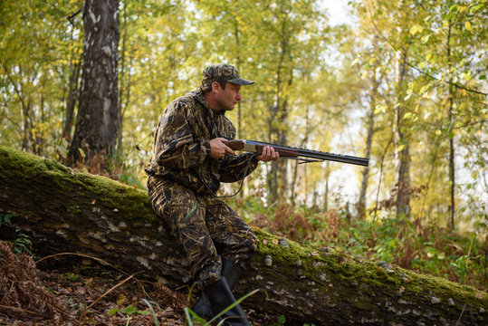 Hunter with a gun in the autumn woods, hunting for a hazel grouse
