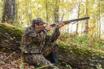 Photo sur Plexiglas Chasser Hunter with a gun in the autumn woods, hunting for a hazel grouse  