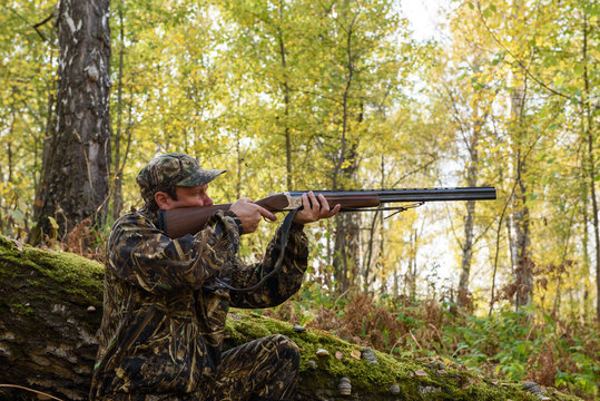 Hunter with a gun in the autumn woods, hunting for a hazel grouse
